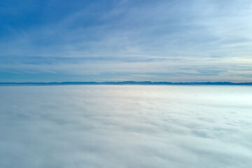 Aerial view from high altitude of earth covered with white puffy cumulus clouds on sunny day