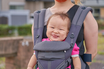 抱っこ紐で抱っこされる笑顔の乳幼児