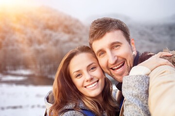 Happy young couple enjoying and posing on winter background