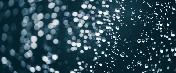 Atmospheric minimal monochrome backdrop with rain droplets on glass. Wet window with rainy drops and dirt spots closeup. Blurry minimalist background of dirty window glass with raindrops close up.