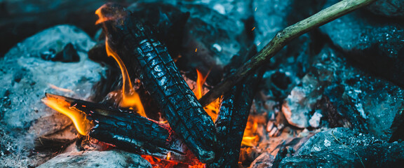 Vivid smoldered firewoods burned in fire close-up. Atmospheric warm background with orange flame of...