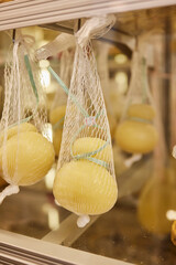 Delicious fresh Caciocavallo and Scamorza cheese hanging. Italian cheeses close up. The cheeses are...