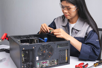 Female technician repairing computer in the room on gray background.