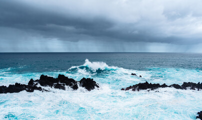 Strong waves on the ocean hitting some rocks and creating water foam