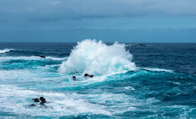 Fototapeta premium Strong waves on the ocean hitting some rocks and creating water foam