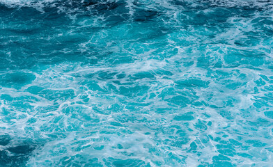 Calm turquoise foamy sea after some waves hitt some rocks