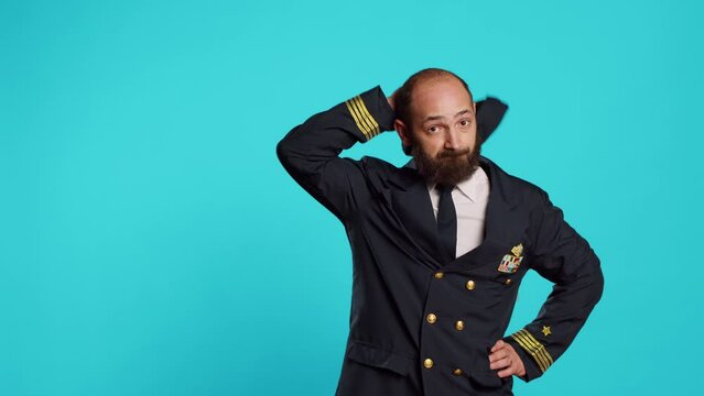 Airline captain raising shoulders and being unsure, shrugging and not knowing answer to question. Young man working as cabin pilot with uniform acting uncertain and clueless on camera.