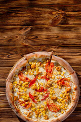 Pizza for children on a cream base with chicken fillet, tomatoes, corn and mozzarella cheese on wood background