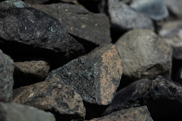 Gray and green pieces of serpentine are loosely piled up at the beach in San Francisco.