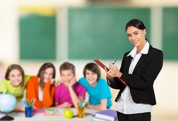 Happy young teacher in class with schoolchild on background.