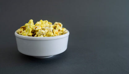 Grey background with a White bowl of popcorn, creative background Popcorn lovers day concept Selective focus
