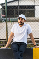 Serene photo of young man in white shirt and cap hat with tennis court in the background