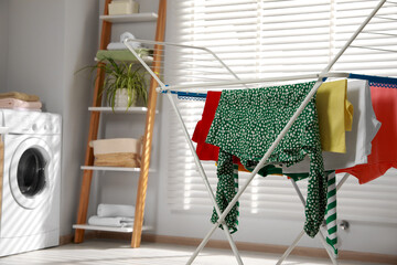 Different apparel drying on clothes airer in bathroom, space for text