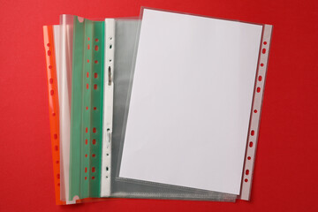 File folders with punched pockets on red background, flat lay