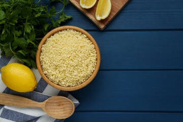 Tasty couscous and ingredients on blue wooden table, flat lay. Space for text