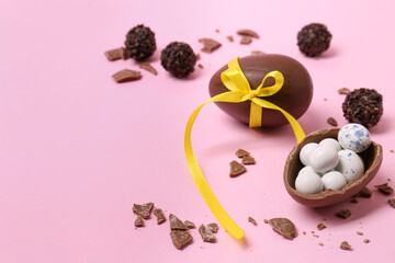 Tasty chocolate eggs and candies on pink background. Space for text