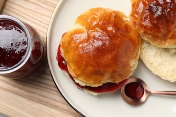 Plate with freshly baked soda water scones and cranberry jam on wooden table, closeup