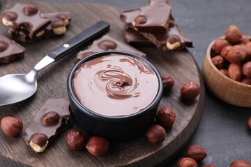 Bowl with tasty paste, chocolate pieces and nuts on grey table