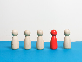 A line of wooden figures with one red color. Stand out of the crowd concept.