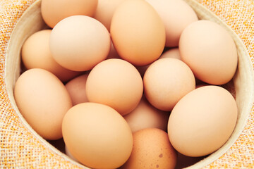 Many eggs. Straw hat. Chicken eggs in wooden basket on green nature floor at cloudy day. Backdrop. Organic food. Springtime. Easter egg. Toned. Out of focus