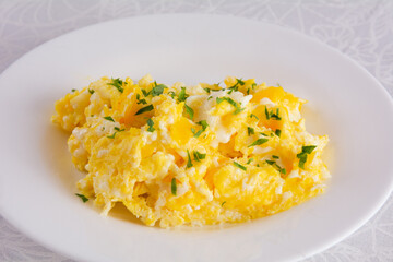 Scrambled eggs on plate, breakfast food, closeup, white background