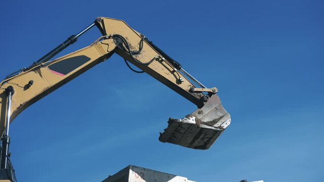 Heavy earth mover with blue sky in the background, slow motion