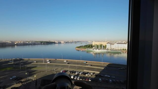 View of the city from above. Saint-Petersburg, Russia. Neva river, city embankment, road with car traffic, bridges. Cruiser Aurora. Person taking photos on professional camera.