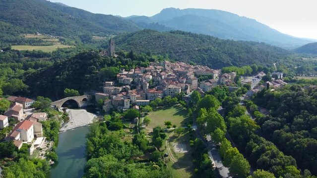 Smooth 4K aerial footage of the medieval town of Olargues featuring the Devil's Bridge in the H&eacute;rault department in the Occitanie region in southern France