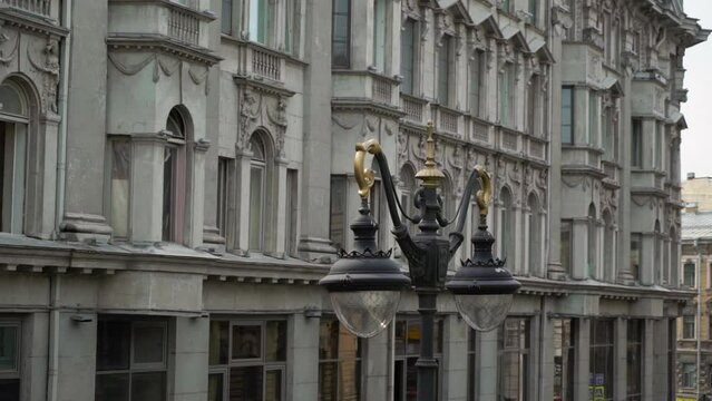 Old historic gray stone building in a European city. Cloudy day, rainy sky. Italian architecture in St. Petersburg. Windows, sculptures, roof and tower.