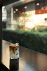 A glass of iced coffee sits on a table in a cafe.