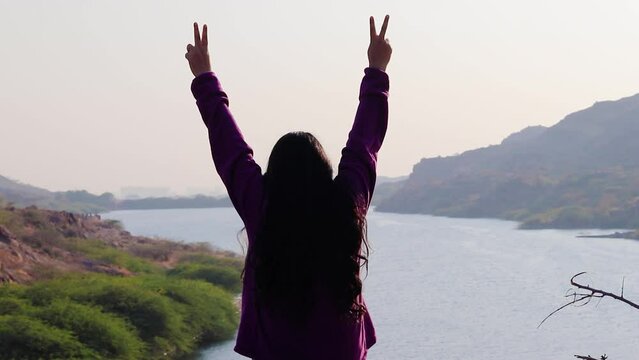 isolated young girl at mountain top with lake view backbit shot from flat angle video is taken at kaylana lake jodhpur rajasthan india.