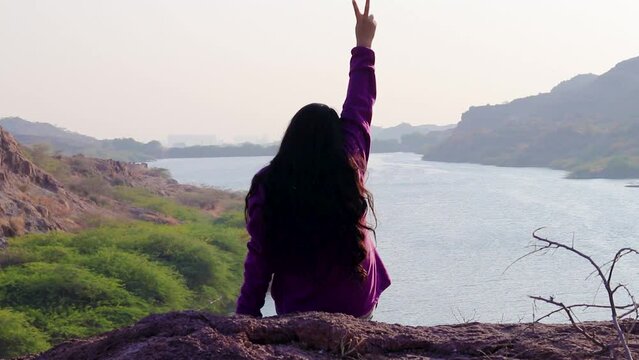 isolated young girl at mountain top with lake view backbit shot from flat angle video is taken at kaylana lake jodhpur rajasthan india.