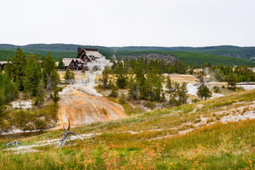 Majestic Geyser erupting in Yellowstone National Park with a rustic backdrop