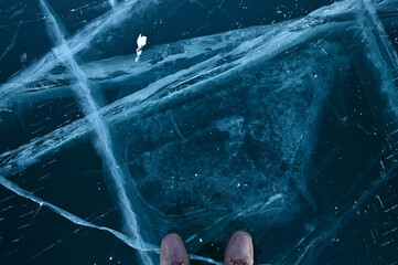 Two Feet Standing on Cracks Surface of Frozen Lake Baikal