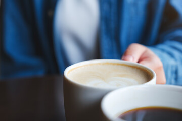 Fototapeta Closeup image of a couple people clinking white coffee mugs in cafe obraz