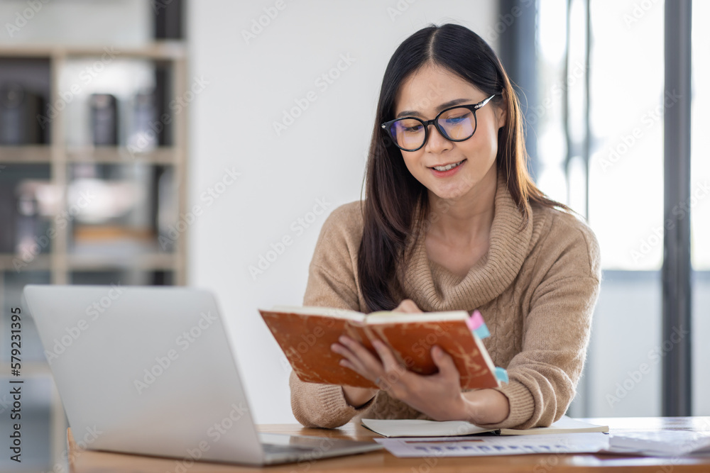 Wall mural Asian Business woman using calculator and laptop for doing math finance on an office desk, tax, report, accounting, statistics, and analytical research concept
