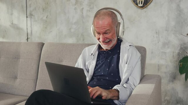 Cheerful old man follower writes social media comment on laptop. Anticipation of the dispute.