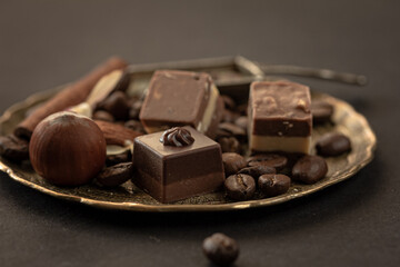 Superfood chocolates, pralines, nuts coffee beans on vintage metallic plate on dark , copy space