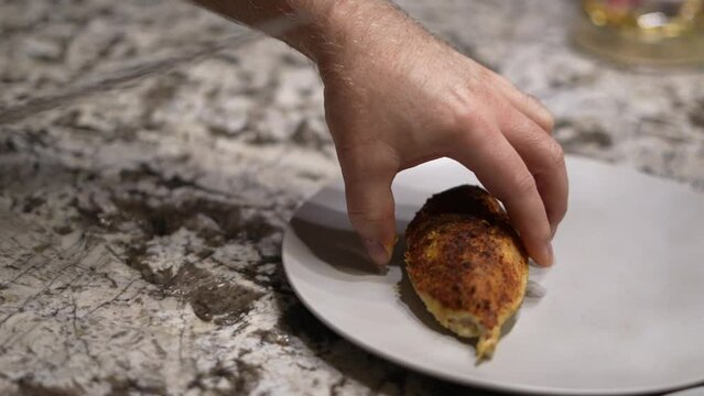 Home chef takes chicken breast from baking tray and puts onto empty plate dish
