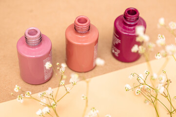 Nail polish of different colors in glass tubes stands on a light background.