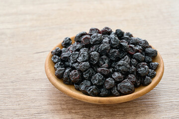 dry blueberry or blackberry in wood plate on wooden table background. pile of dry blueberry or blackberry. dry blueberry or blackberry