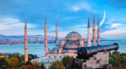Obraz premium Ramadan Concept - Sultanahmet mosque and Bosphorus with crescent moon and cannon at twilight blue hour - Istanbul, Turkey