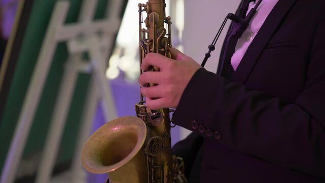 Saxophonist plays music. Musician blowing saxophone. Wind musical instruments - sax. Artist performs on stage, band concert, jazz festival