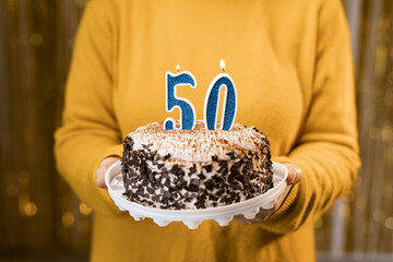 Woman holding a festive cake with number 50 candles while celebrating birthday party. Birthday...