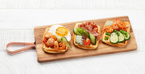 Breakfast waffles with fried eggs, salmon, cucumber and prawns