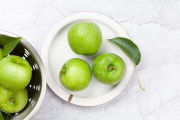 Fresh green apples in colander on stone table