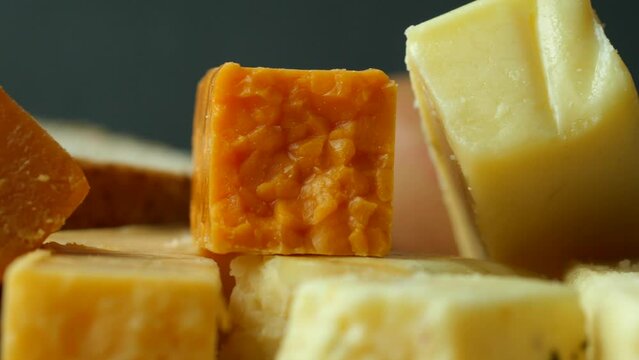 Cheese cubes green, yellow and red color on chopping board 