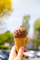 Female hand holding delicious american vanilla chocolate ice cream. Tasty homemade icecream Gelato in the waffle cone. Gluten free vegan dairy free ice cream. 