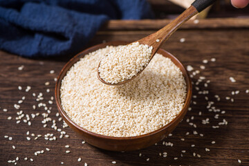 white sesame seeds in wooden bowl on table.