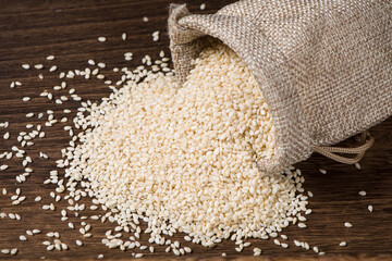 white sesame seeds in sack on wooden table